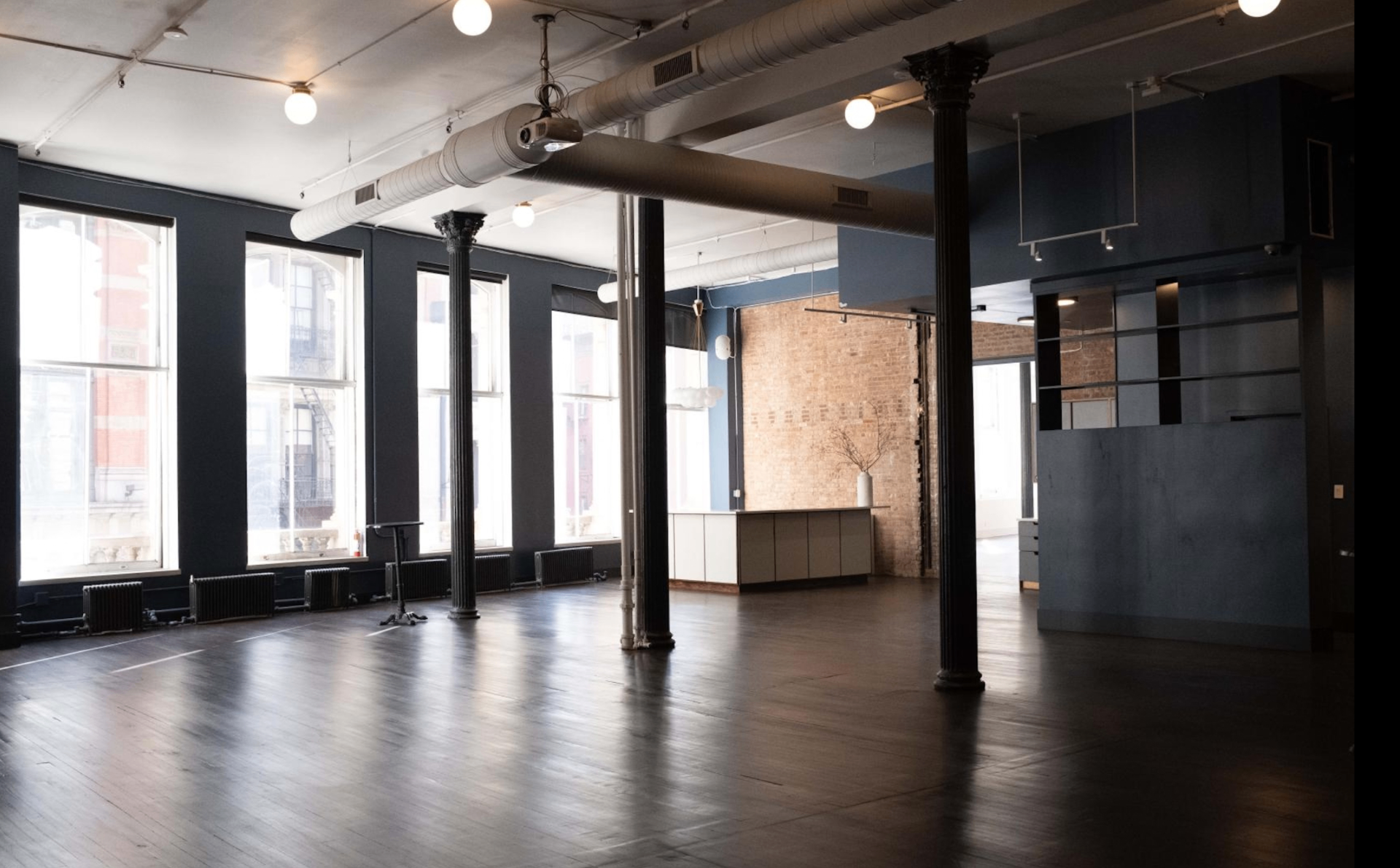 Venue main hall with large windows, dark walls, and wooden flooring